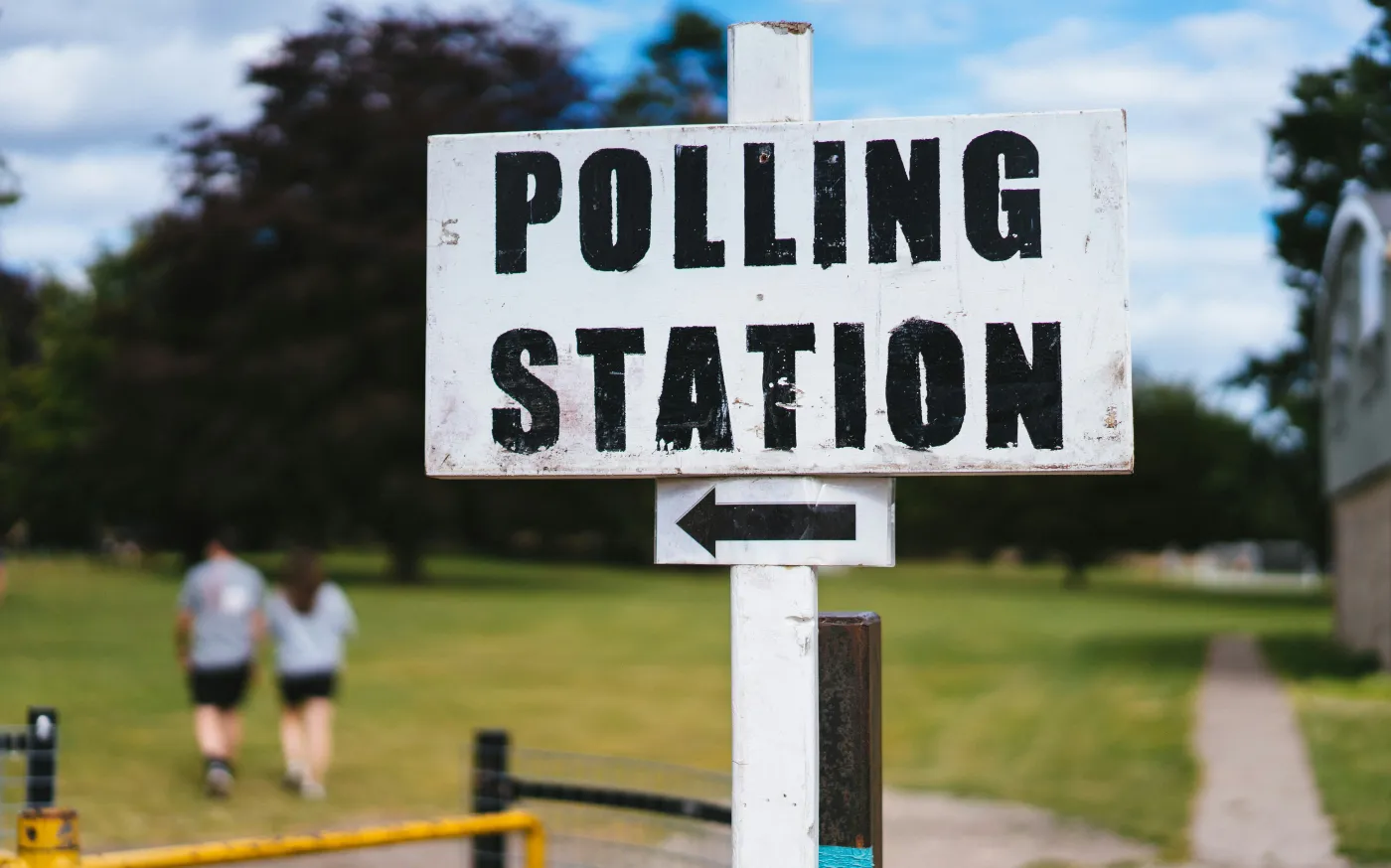 A pole with a sign that says polling station by Phil Hearing courtesy of Unsplash.